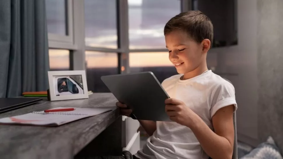 Siswa tersenyum gembira saat belajar menggunakan tablet murah 2026 untuk sekolah di meja belajar
