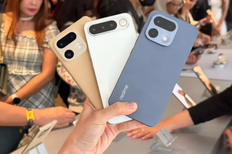 Seseorang memegang tiga unit HP Realme kamera 200MP dengan opsi warna emas, putih, dan biru di sebuah pameran gadget.