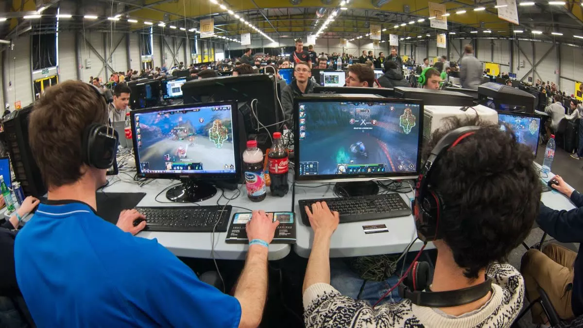 Para gamer sedang bermain gim di PC dalam ruangan besar, menikmati promo game PC diskon bersama.
