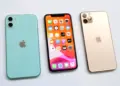 Tiga unit iPhone bekas varian warna Green, layar depan aktif, dan Gold bersandingan di latar putih.
