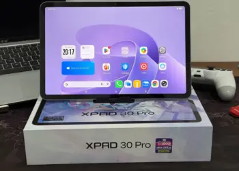 Tablet Infinix XPAD 30 Pro dengan layar menyala menampilkan antarmuka Android, diletakkan di atas kotak kemasan resminya.