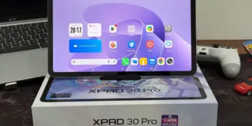 Tablet Infinix XPAD 30 Pro dengan layar menyala menampilkan antarmuka Android, diletakkan di atas kotak kemasan resminya.