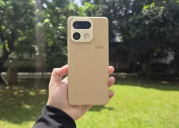 Bodi belakang HP kamera 200 MP realme warna krem bertekstur kulit dipegang tangan di luar ruangan