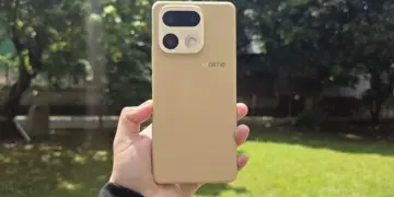 Bodi belakang HP kamera 200 MP realme warna krem bertekstur kulit dipegang tangan di luar ruangan