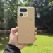 Bodi belakang HP kamera 200 MP realme warna krem bertekstur kulit dipegang tangan di luar ruangan