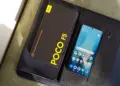 HP Xiaomi RAM 8 GB dengan layar menyala bersanding dengan boks penjualan bertuliskan POCO F5 5G.