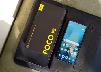HP Xiaomi RAM 8 GB dengan layar menyala bersanding dengan boks penjualan bertuliskan POCO F5 5G.