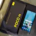 HP Xiaomi RAM 8 GB dengan layar menyala bersanding dengan boks penjualan bertuliskan POCO F5 5G.