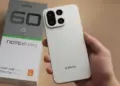 Tangan memegang smartphone Infinix Note 60 Pro warna putih beserta kotak kemasannya.