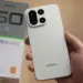 Tangan memegang smartphone Infinix Note 60 Pro warna putih beserta kotak kemasannya.