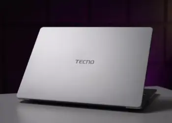 Tampilan cover belakang laptop TECNO berwarna silver minimalis di atas meja.