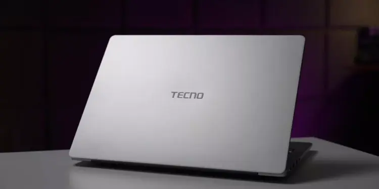 Tampilan cover belakang laptop TECNO berwarna silver minimalis di atas meja.