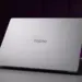 Tampilan cover belakang laptop TECNO berwarna silver minimalis di atas meja.