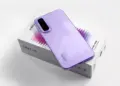 Smartphone Infinix Hot 70 warna ungu diletakkan di atas kotak kemasan produk.
