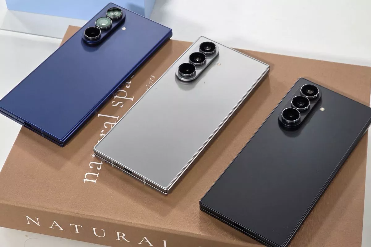 Tiga HP Samsung Galaxy Z Fold lipat berwarna biru, perak, dan hitam tergeletak di atas kotak.