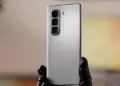 Tampilan bodi belakang HP Infinix murah warna perak dengan tiga kamera vertikal yang dipegang tangan.