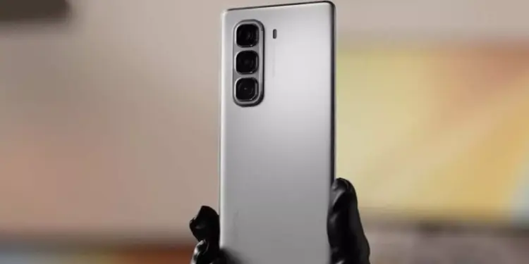 Tampilan bodi belakang HP Infinix murah warna perak dengan tiga kamera vertikal yang dipegang tangan.