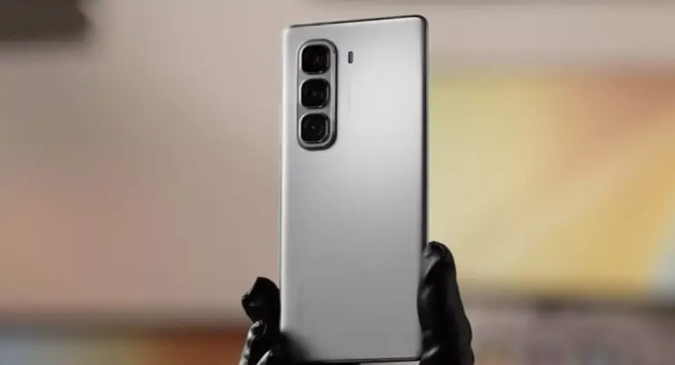 Tampilan bodi belakang HP Infinix murah warna perak dengan tiga kamera vertikal yang dipegang tangan.