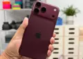 Seseorang menggenggam iPhone 18 Pro warna merah marun dengan desain modul kamera baru yang mendukung fitur anti foto AI.