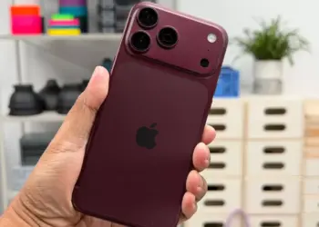 Seseorang menggenggam iPhone 18 Pro warna merah marun dengan desain modul kamera baru yang mendukung fitur anti foto AI.