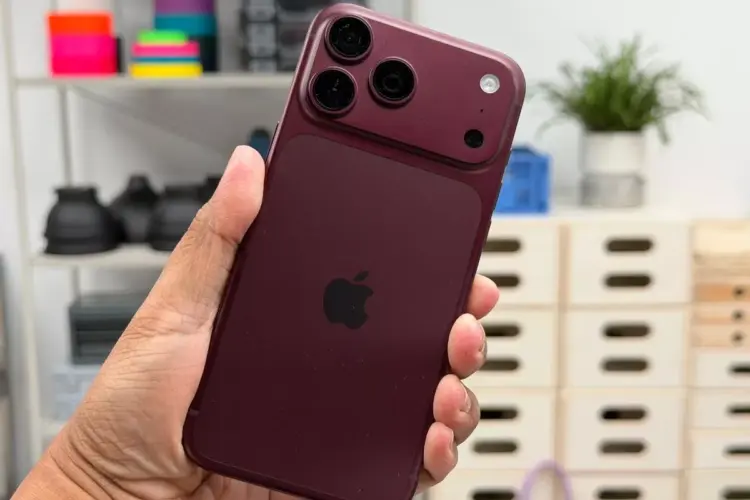 Seseorang menggenggam iPhone 18 Pro warna merah marun dengan desain modul kamera baru yang mendukung fitur anti foto AI.