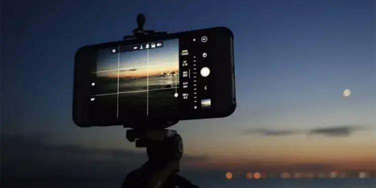 Smartphone terpasang di tripod memotret pemandangan matahari terbenam dengan mode manual kamera
