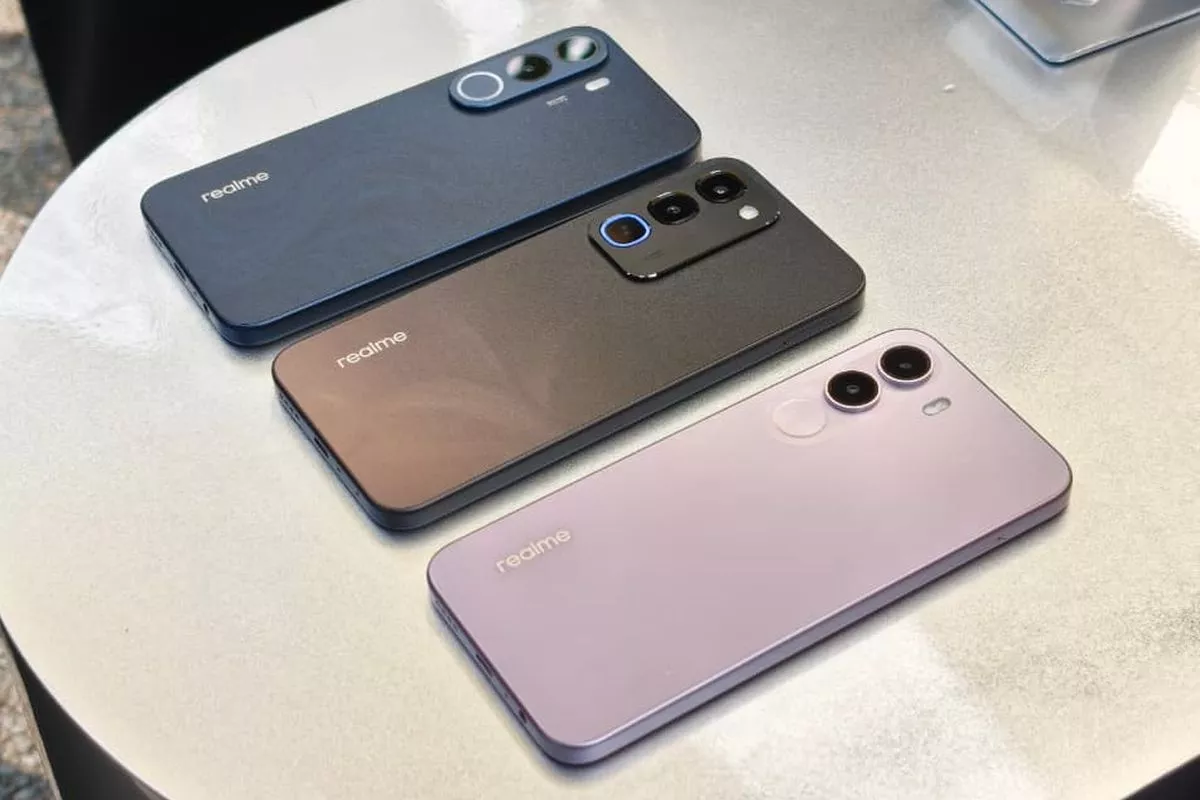 Tiga unit HP 4 Jutaan merek Realme berwarna biru tua, hitam metalik, dan ungu muda tergeletak di atas meja.