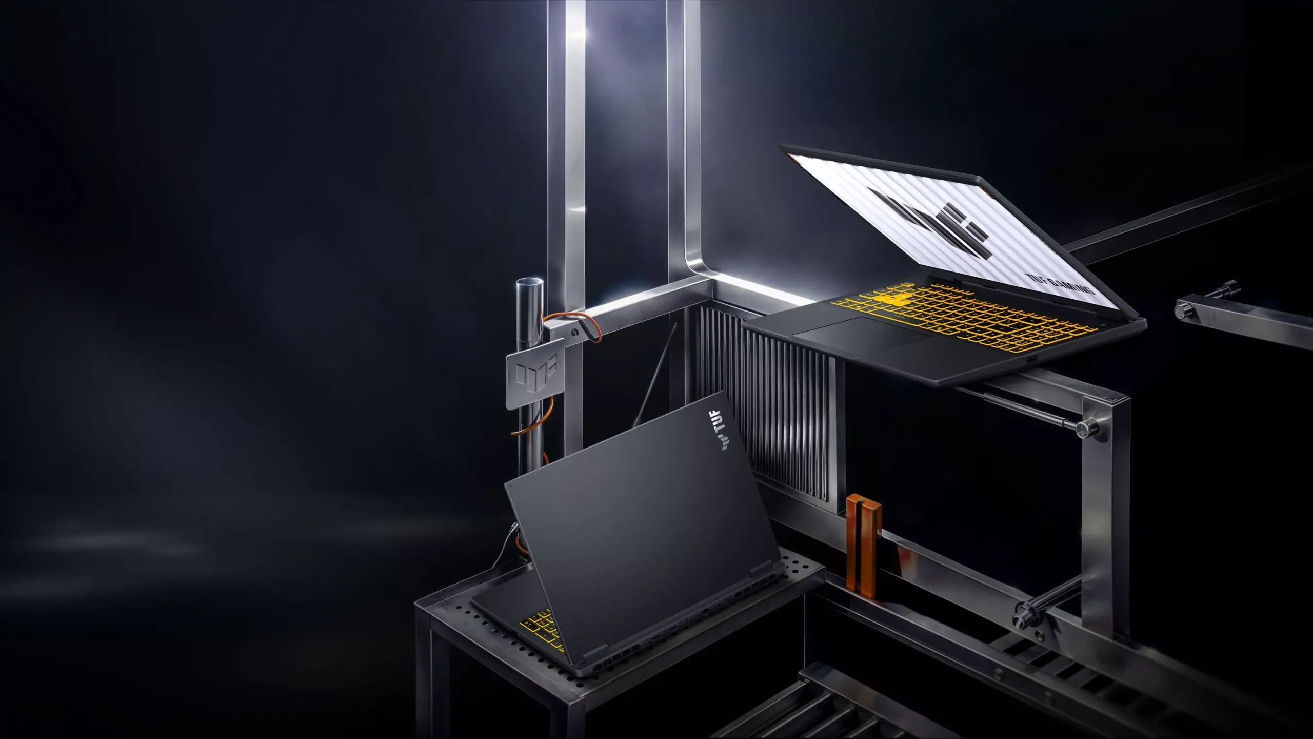 Tampilan bodi dan keyboard laptop ASUS TUF Gaming 16 FX610 pada set panggung industrial yang elegan.