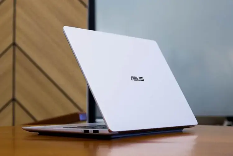 Tampilan bodi belakang ASUS Vivobook S14 S5452MA berbahan metal tipis dan elegan di atas meja kayu.
