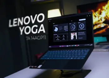 Laptop Lenovo Yoga Slim 7a 14AGP11 berwarna gelap diletakkan di atas stand laptop meja kerja studio.