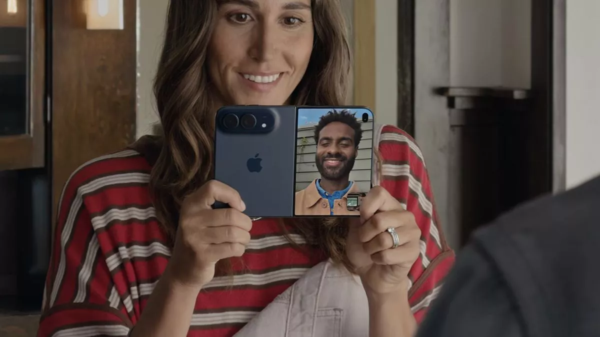 Seorang wanita memegang iPhone Duo dalam mode layar ganda untuk panggilan video.