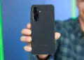 Tangan memegang HP Samsung 5G berwarna hitam memperlihatkan modul tiga kamera belakang.