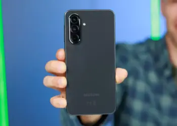 Tangan memegang HP Samsung 5G berwarna hitam memperlihatkan modul tiga kamera belakang.