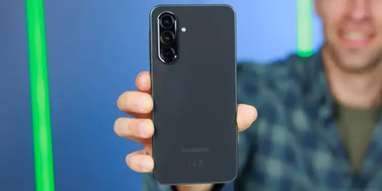 Tangan memegang HP Samsung 5G berwarna hitam memperlihatkan modul tiga kamera belakang.