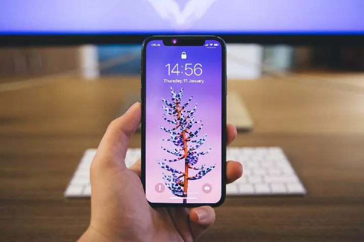 Seseorang sedang memegang perangkat iPhone lama untuk mengoptimalkan kinerjanya.