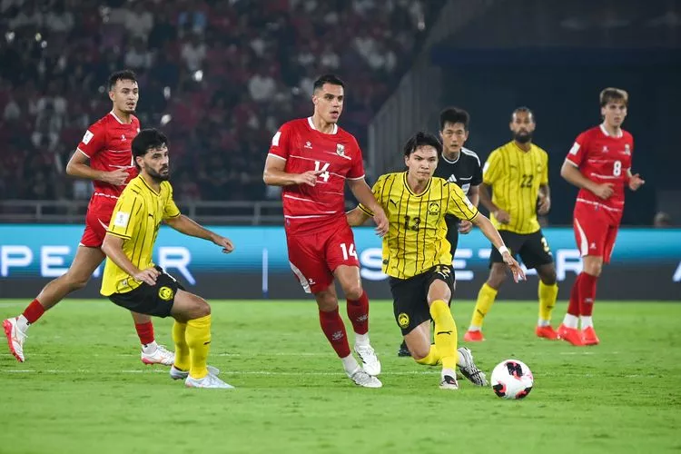 Pemain Timnas Indonesia berseragam merah berebut bola dengan pemain lawan di tengah pertandingan