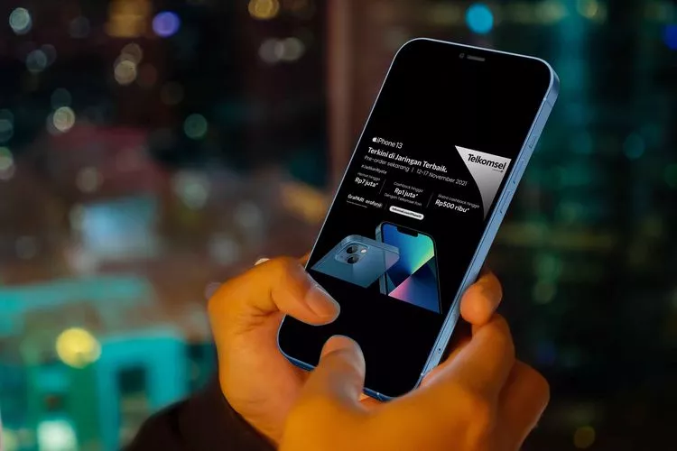 Pengguna menggenggam smartphone yang menampilkan promo paket bundel Telkomsel.