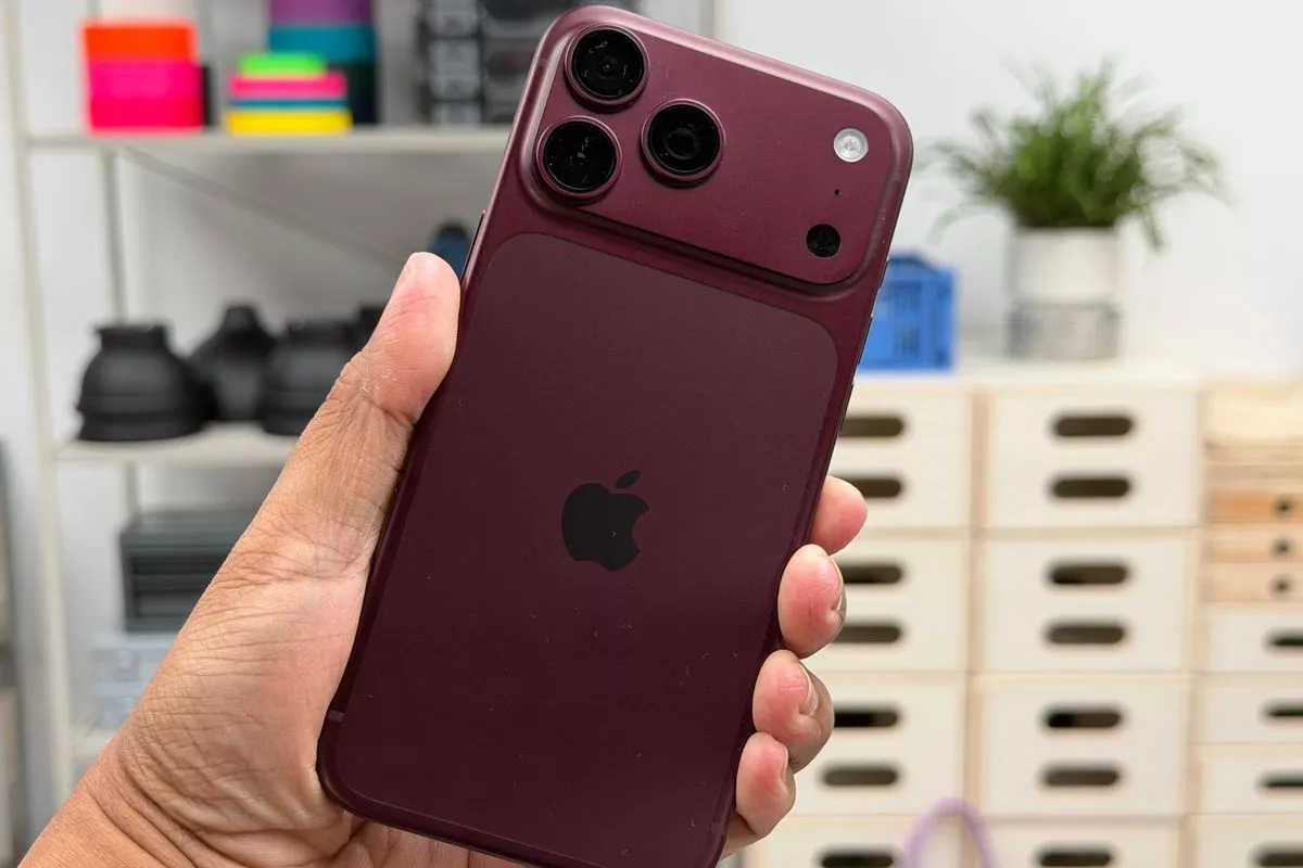 Tampilan bagian belakang perangkat iPhone 18 Pro berwarna merah maroon dalam genggaman.