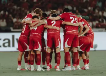 Timnas Indonesia berkumpul di tengah lapangan, saling merangkul, menciptakan momen persatuan yang kuat.