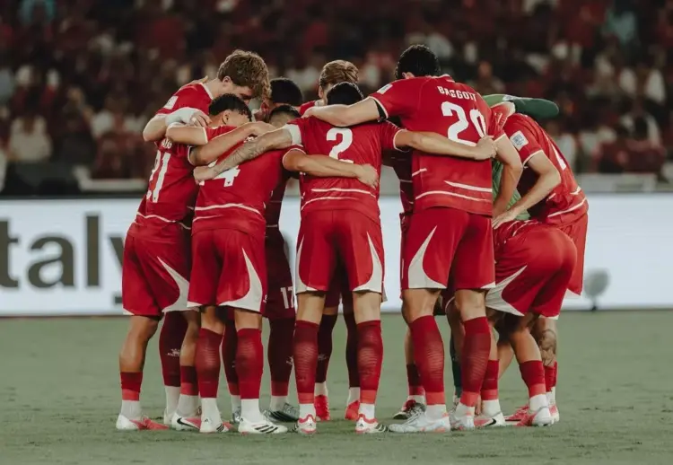 Timnas Indonesia berkumpul di tengah lapangan, saling merangkul, menciptakan momen persatuan yang kuat.