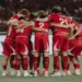 Timnas Indonesia berkumpul di tengah lapangan, saling merangkul, menciptakan momen persatuan yang kuat.