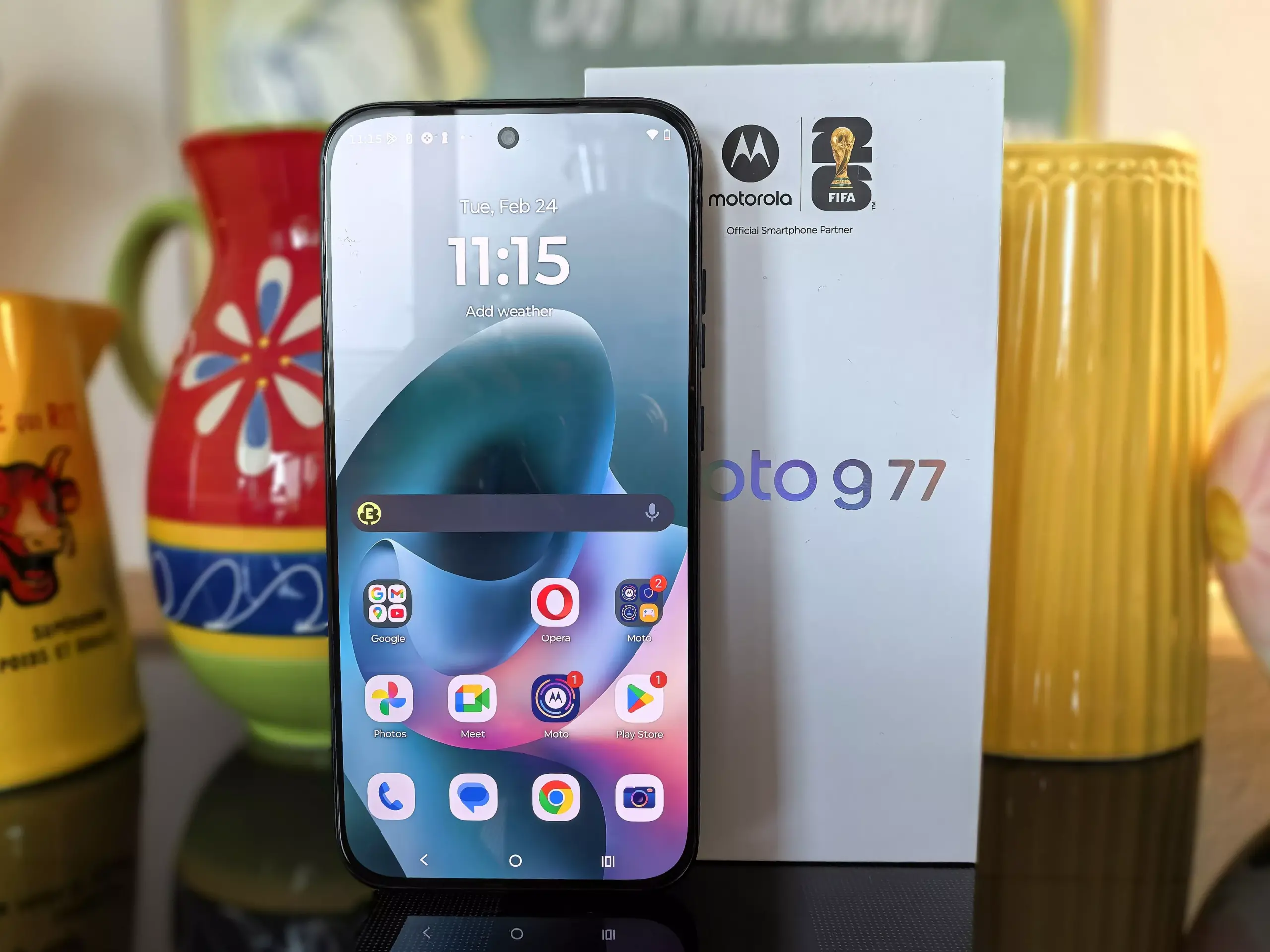 Tampilan layar utama Moto G77 dengan kotak penjualan di latar belakang.