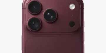 Close up modul kamera belakang tiga lensa pada konsep bodi merah maroon dalam isu penyesuaian produksi iPhone 18 Pro.