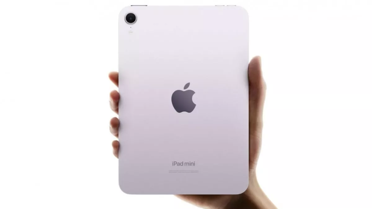 Tangan memegang bodi belakang iPad Mini 8 warna ungu muda.