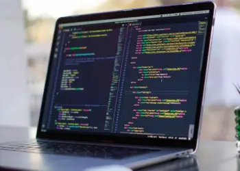 Layar laptop menampilkan baris kode pemrograman HTML dan CSS untuk kebutuhan mahasiswa informatika