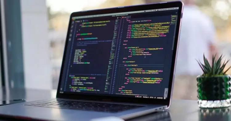Layar laptop menampilkan baris kode pemrograman HTML dan CSS untuk kebutuhan mahasiswa informatika