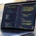 Layar laptop menampilkan baris kode pemrograman HTML dan CSS untuk kebutuhan mahasiswa informatika