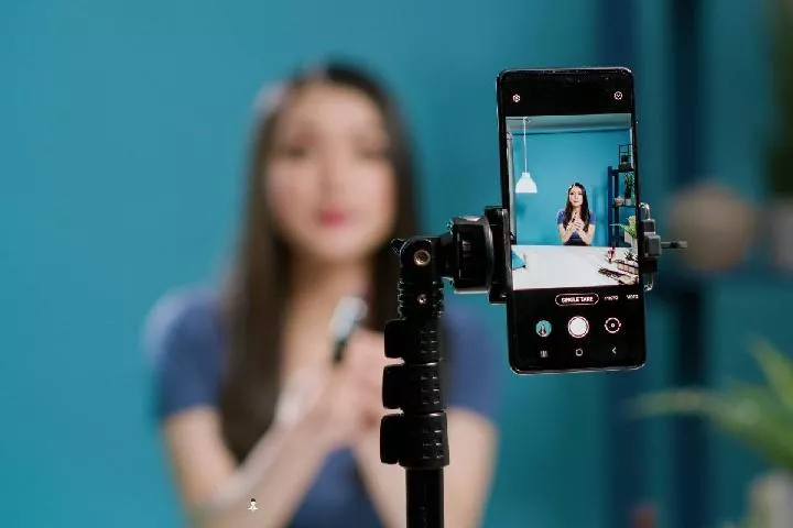 Penggunaan HP content creator yang dipasang pada tripod untuk perekaman video vlogging.